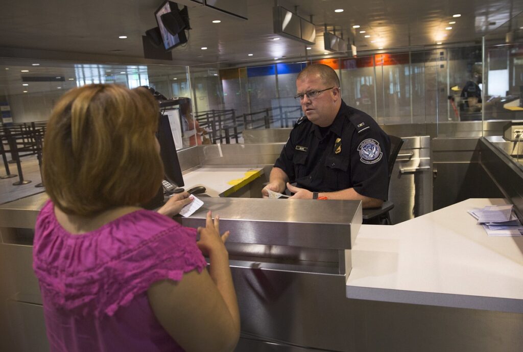 CBP officer inspects travel documents for noncitizen