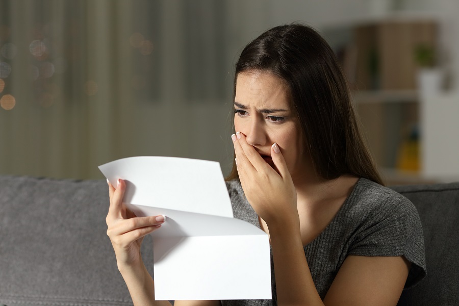 Woman covers mouth after receiving USCIS letter with a Form I 485 Denial