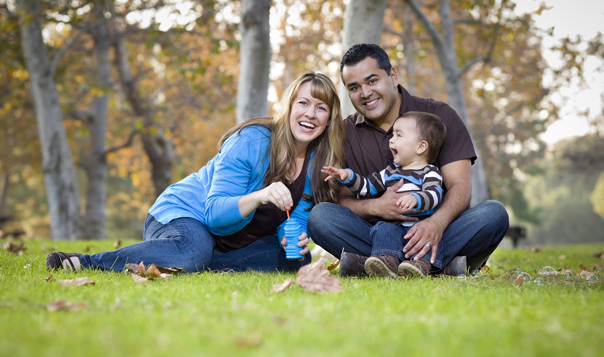 Family sits on grass after successfully proving a bona fide marriage on Form I-751