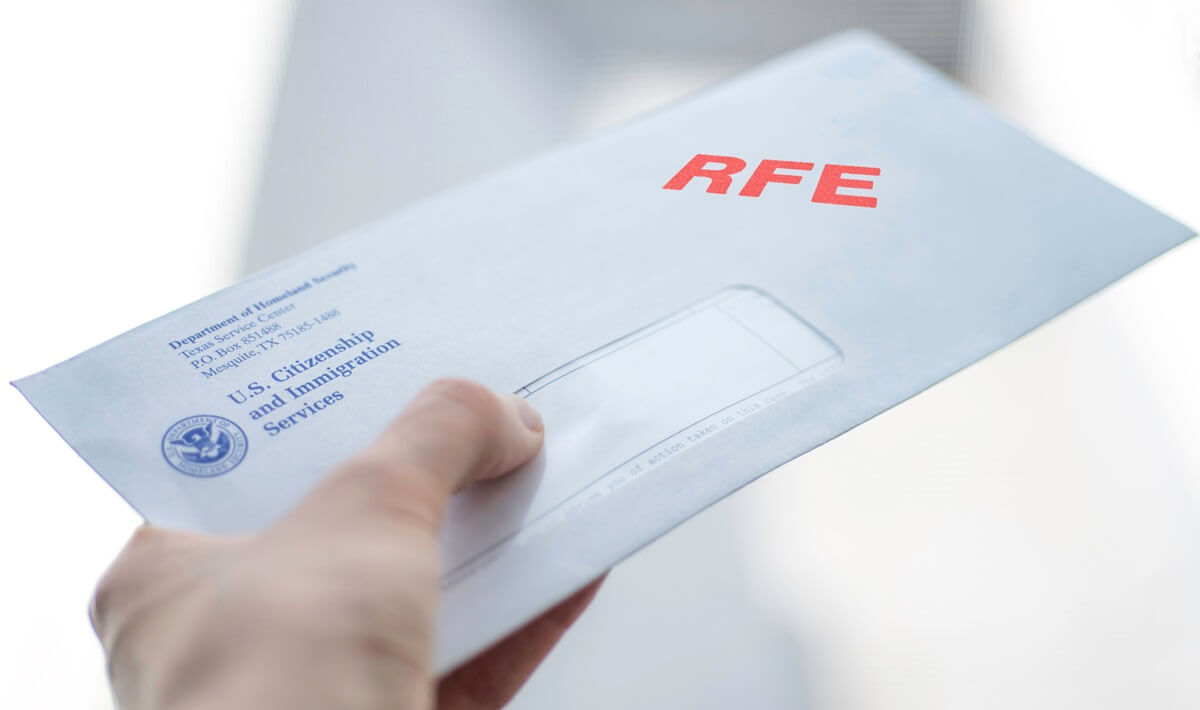 Hand holds an I-485 RFE letter from USCIS